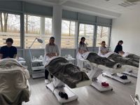 Das Team von Beauty Connection München in schwarzen Roben und mit Abschlusskappen, vereint und professionell.
