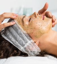 Frau während einer Kräuterpeeling-Behandlung, durchgeführt in der Beauty Connection München.