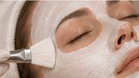 Kosmetikerin trägt eine pflegende Gesichtsmaske als Behandlungs-Upgrade auf