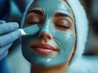 Auftragen einer Gesichtsmaske mit Pinsel während einer kosmetischen Behandlung in der Ausbildung